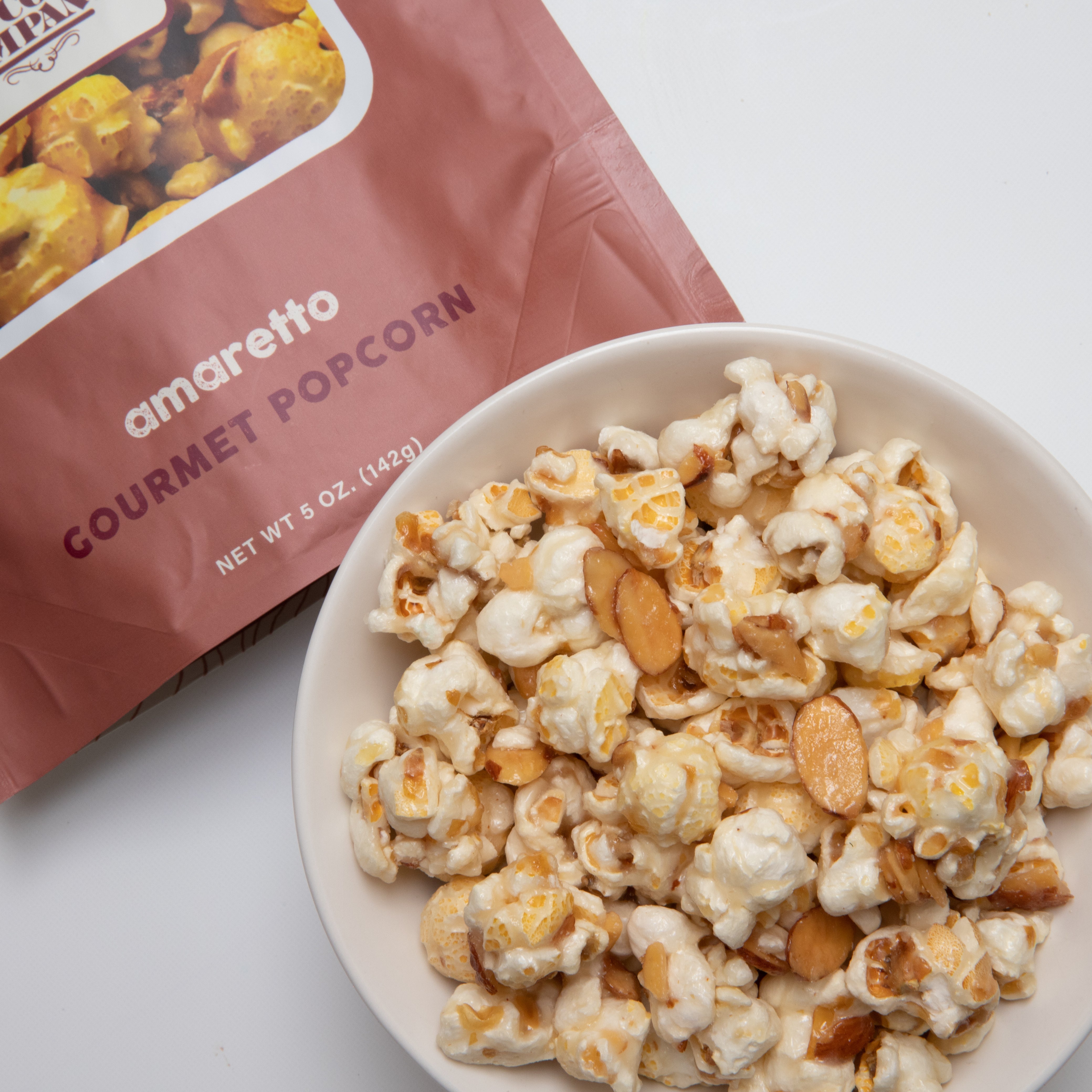 Amaretto flavored popcorn in a 5 oz bag from Colorado Popcorn Company, showcasing golden, coated popcorn pieces.