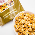 Caramel peanut popcorn in a clear bag from Colorado Popcorn Company, 5 oz, with caramel-coated popcorn and roasted peanuts visible.