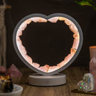 Rose quartz heart-shaped night light called Love Magnet by Conscious Items, emits a soft glow and serves as a calming decor piece.