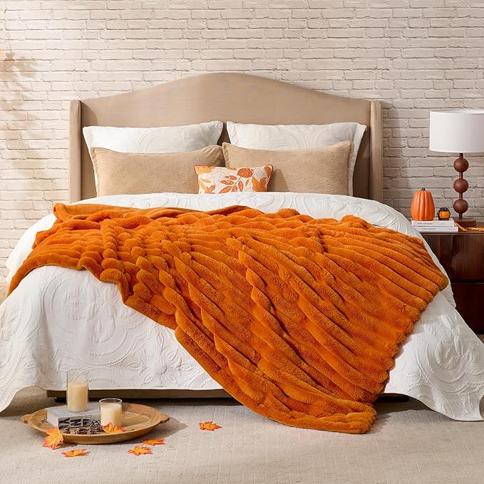 CozyNest Decor fall harvest faux fur throw blanket in burnt orange, plush striped design on a sofa for cozy home decor.