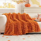 CozyNest Decor fall harvest faux fur throw blanket in burnt orange, plush striped design on a sofa for cozy home decor.