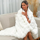 CozyNest Decor ivory faux fur throw blanket with plush, fluffy double-sided rabbit fur texture on a bed for winter warmth.