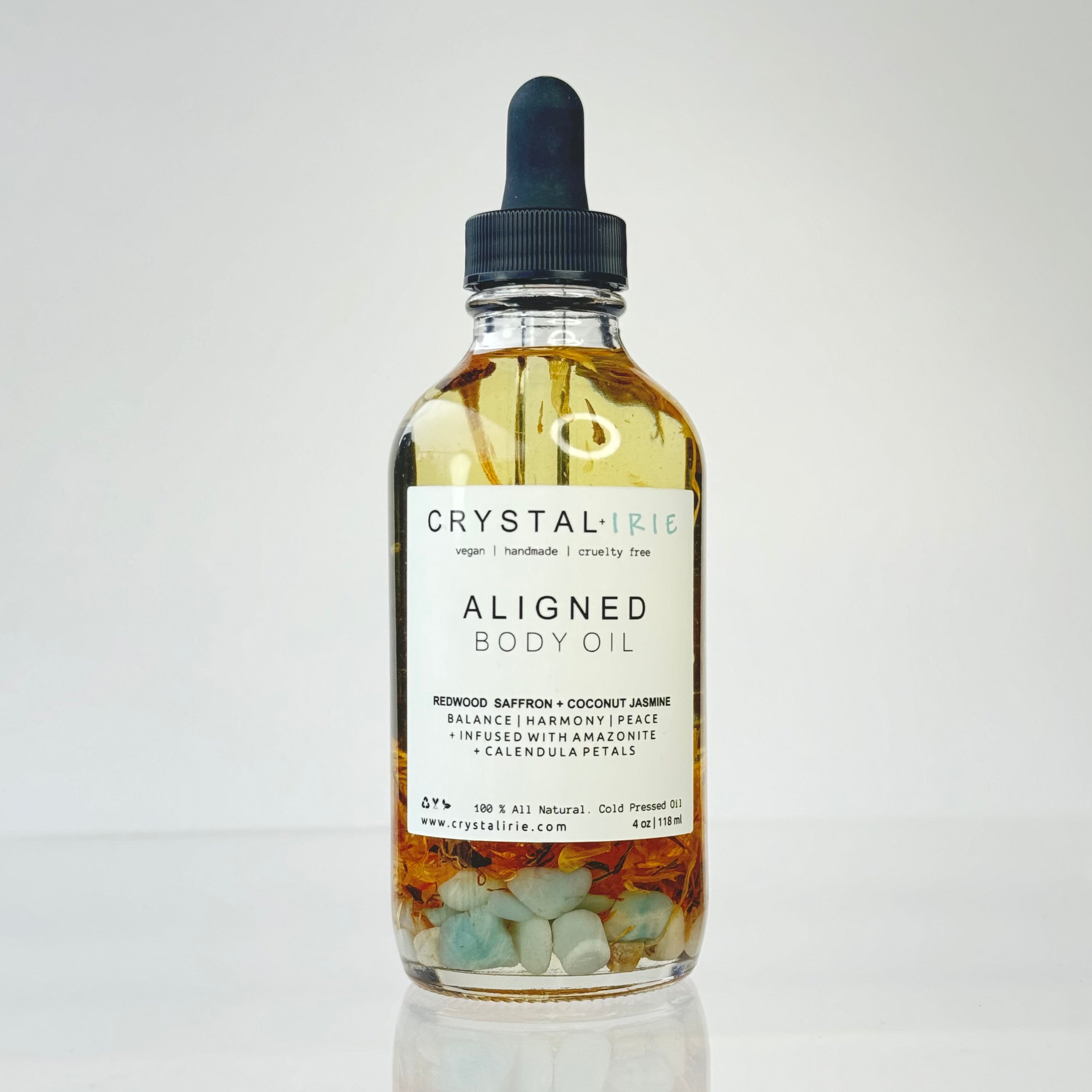 Crystal Irie Aligned Body Oil bottle showing a sleek glass container with a golden cap and a minimalistic label, full view.