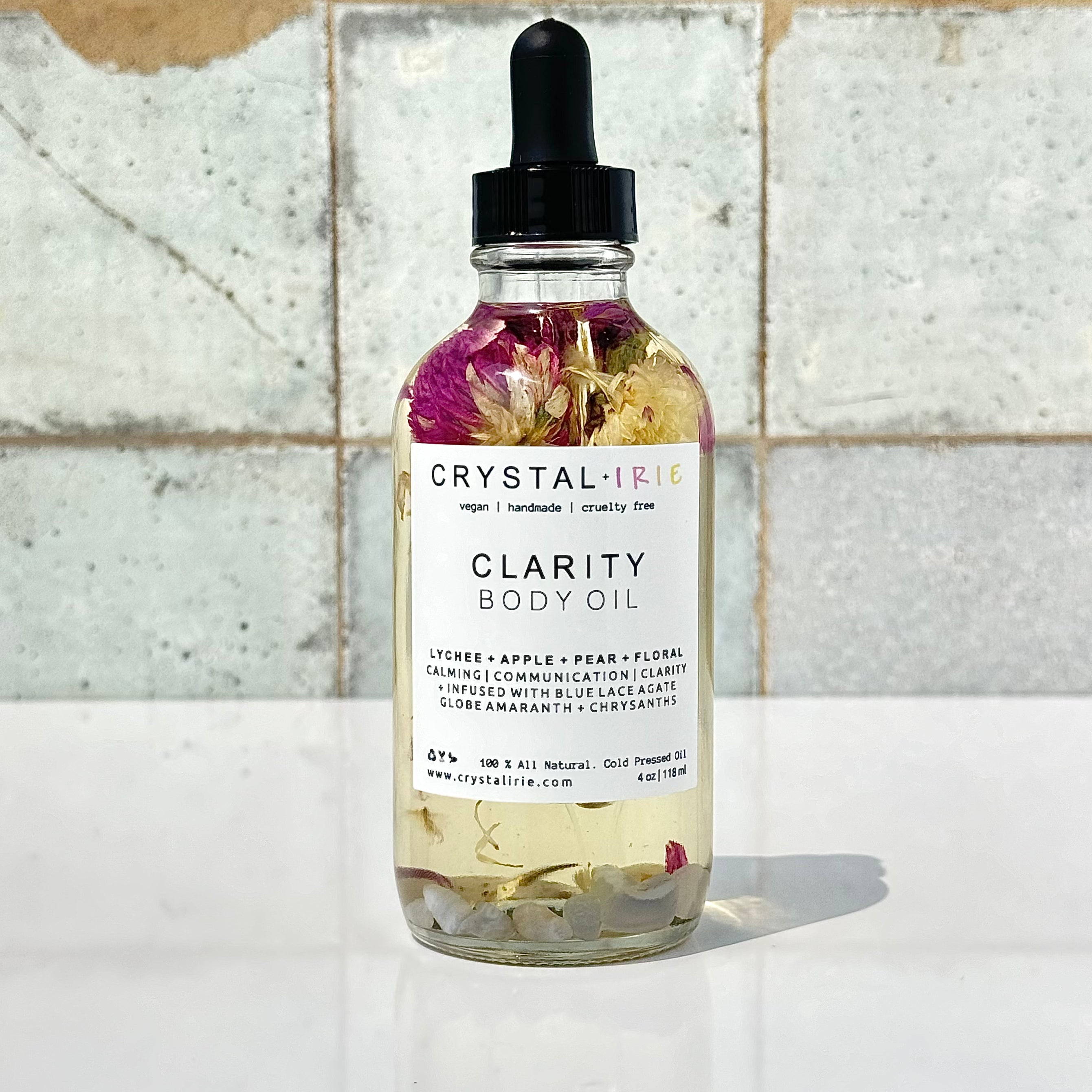 Crystal Irie Clarity Body Oil bottle with clear liquid and minimalist label on a white background.