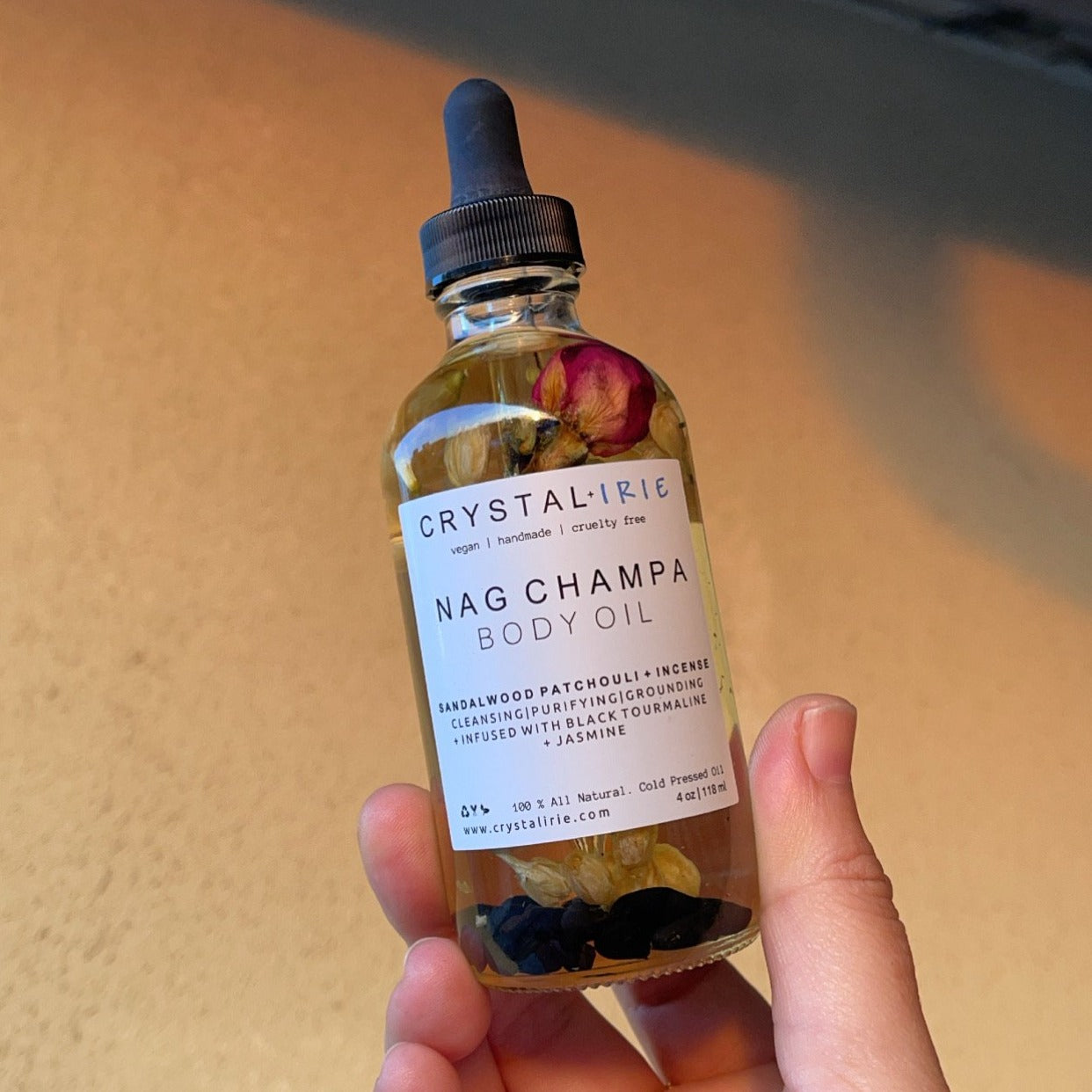 Crystal Irie Nag Champa Body Oil bottle with golden liquid and label, used for aromatherapy and skin nourishment.