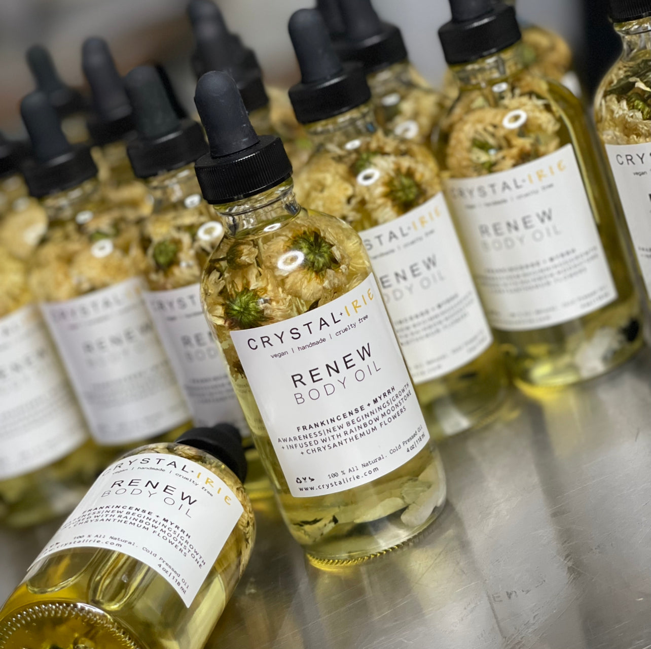Crystal Irie ReNew Body Oil bottle with pump dispenser, showcasing the nourishing body oil in a sleek glass container.