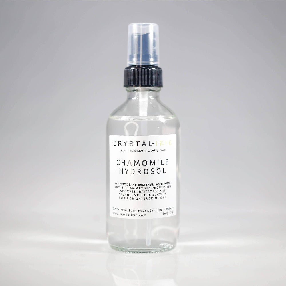 Bottle of Crystal Irie Chamomile Hydrosol with fresh chamomile flowers, showcasing a clear, soothing botanical facial mist.