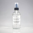 Bottle of Crystal Irie Chamomile Hydrosol with fresh chamomile flowers, showcasing a clear, soothing botanical facial mist.