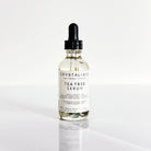 Crystal Irie Tea Tree Serum in a glass bottle, featuring a dropper applicator and fresh tea tree leaves in the background.