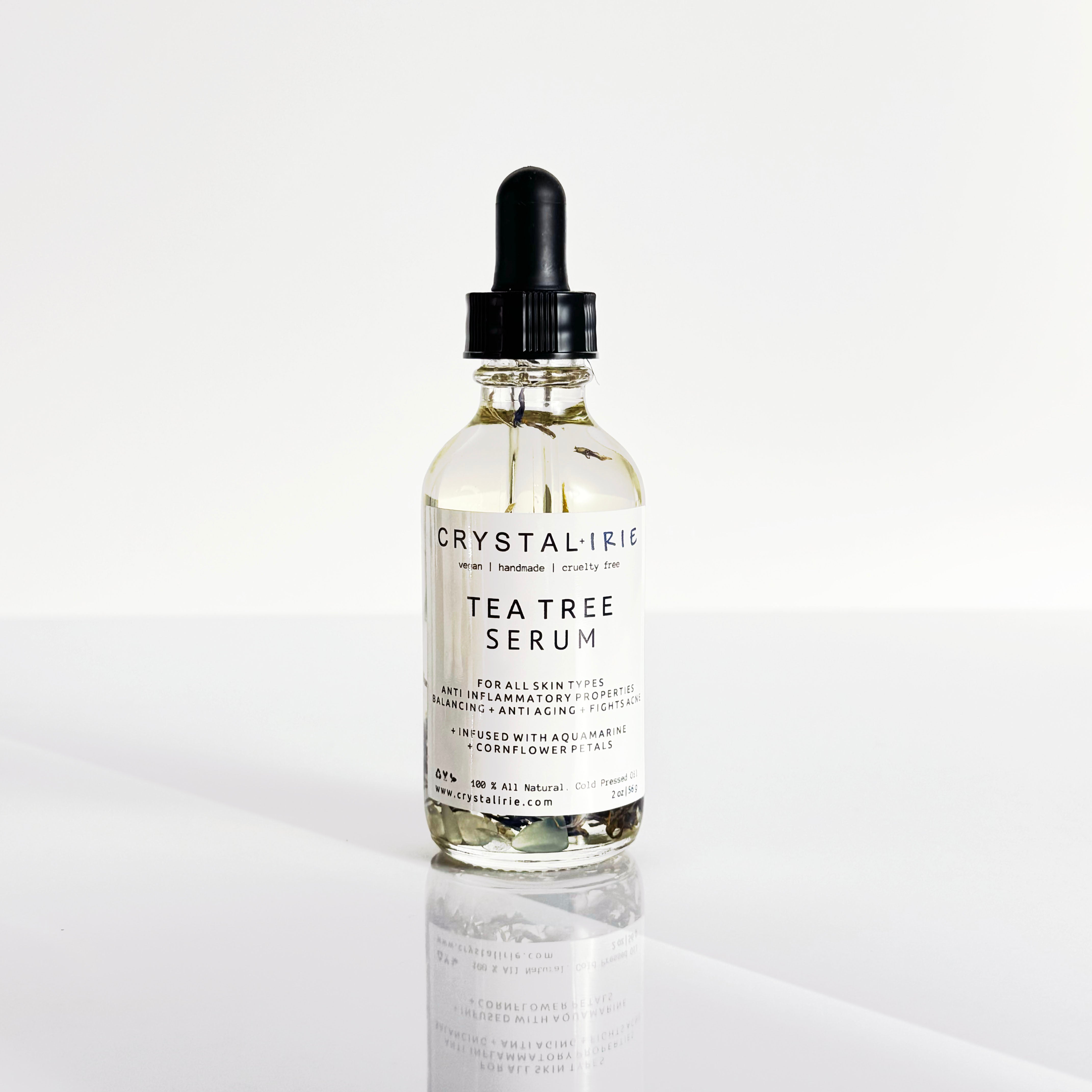 Crystal Irie Tea Tree Serum in a glass bottle, featuring a dropper applicator and fresh tea tree leaves in the background.