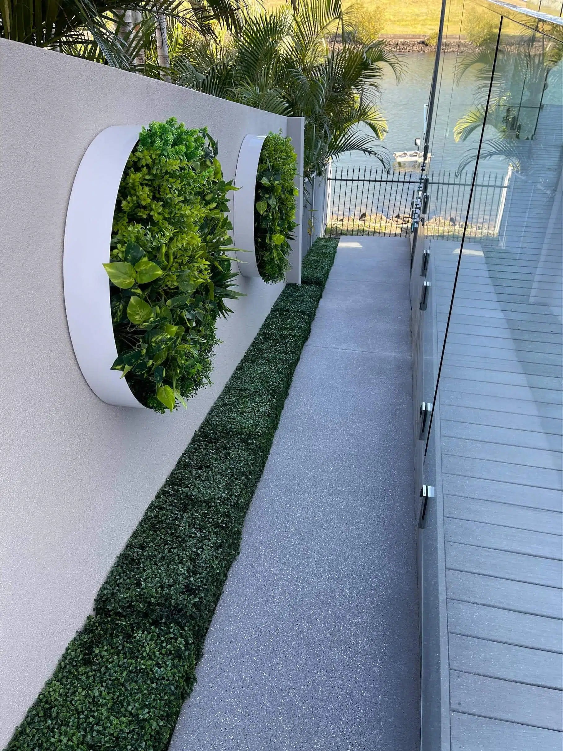 Green artificial hedge panel by Designer Plants USA, UV resistant and suitable for commercial use, with a portable hedge below.