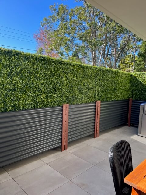 Dark green artificial boxwood hedge in planter boxes, UV resistant commercial grade hedge wall by Designer Plants USA.