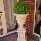 Set of 2 17-inch UV-resistant artificial topiary balls by Designer Plants USA on decorative urns, ideal for outdoor decor.