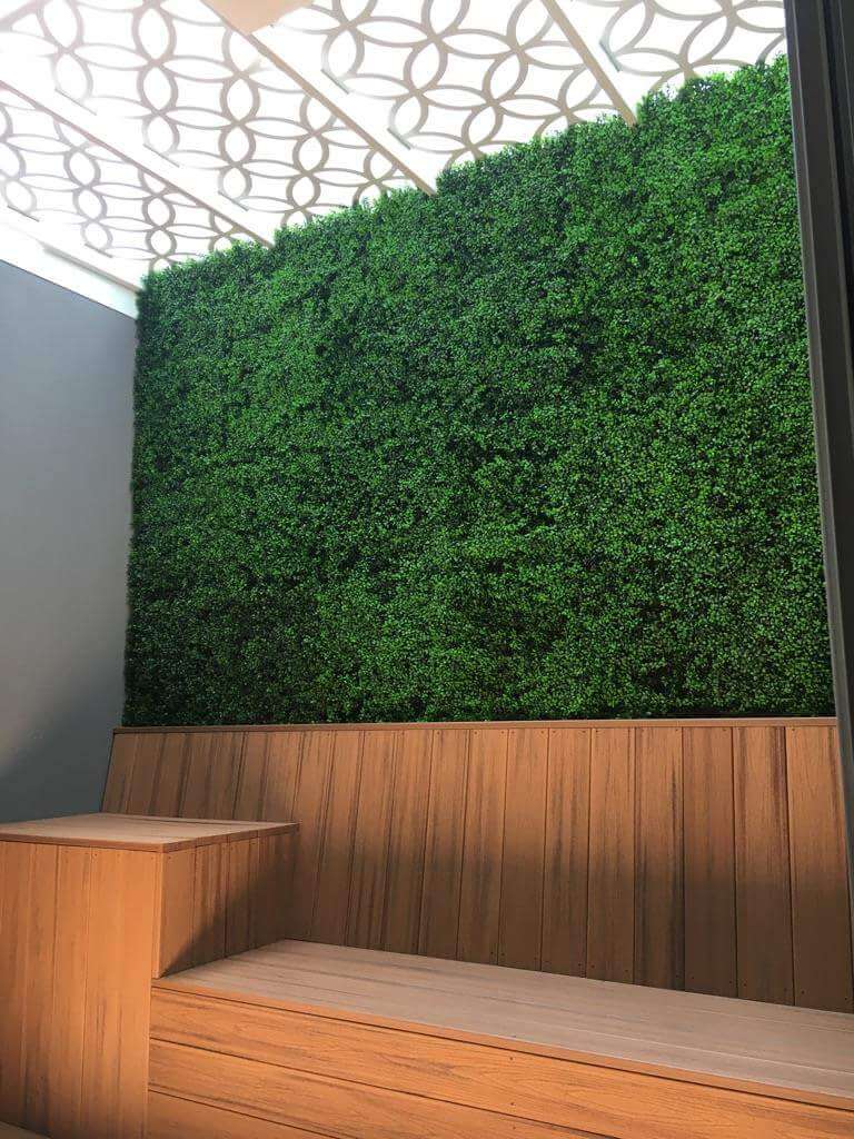 Near-natural green boxwood vertical garden wall panel by Designer Plants USA installed outdoors in a cafe, UV resistant and commercial grade.