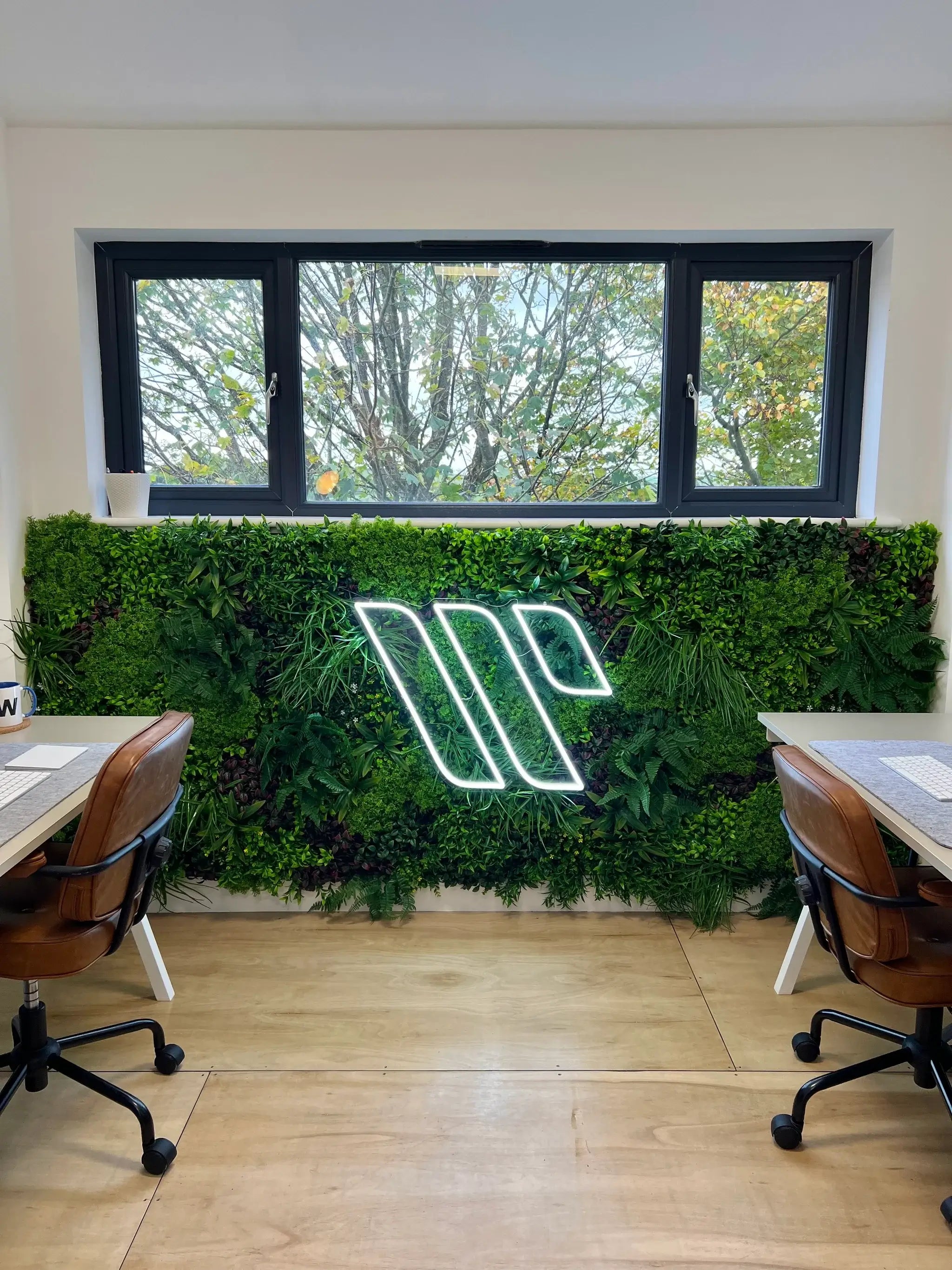 Office signage with a 40x40 inch Designer Plants USA artificial green wall panel displaying a lush, UV-resistant living wall in an office setting.