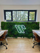 Office signage with a 40x40 inch Designer Plants USA artificial green wall panel displaying a lush, UV-resistant living wall in an office setting.