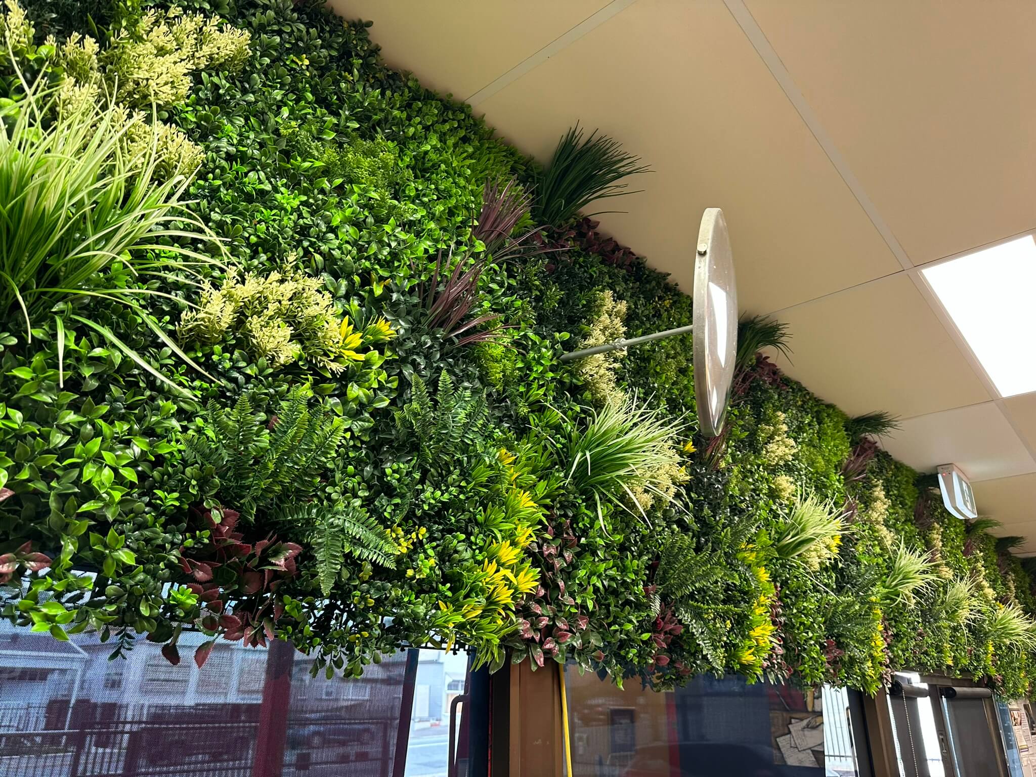 Artificial vertical garden wall panels by Designer Plants USA, featuring lush evergreen triptych panels for commercial green walls.