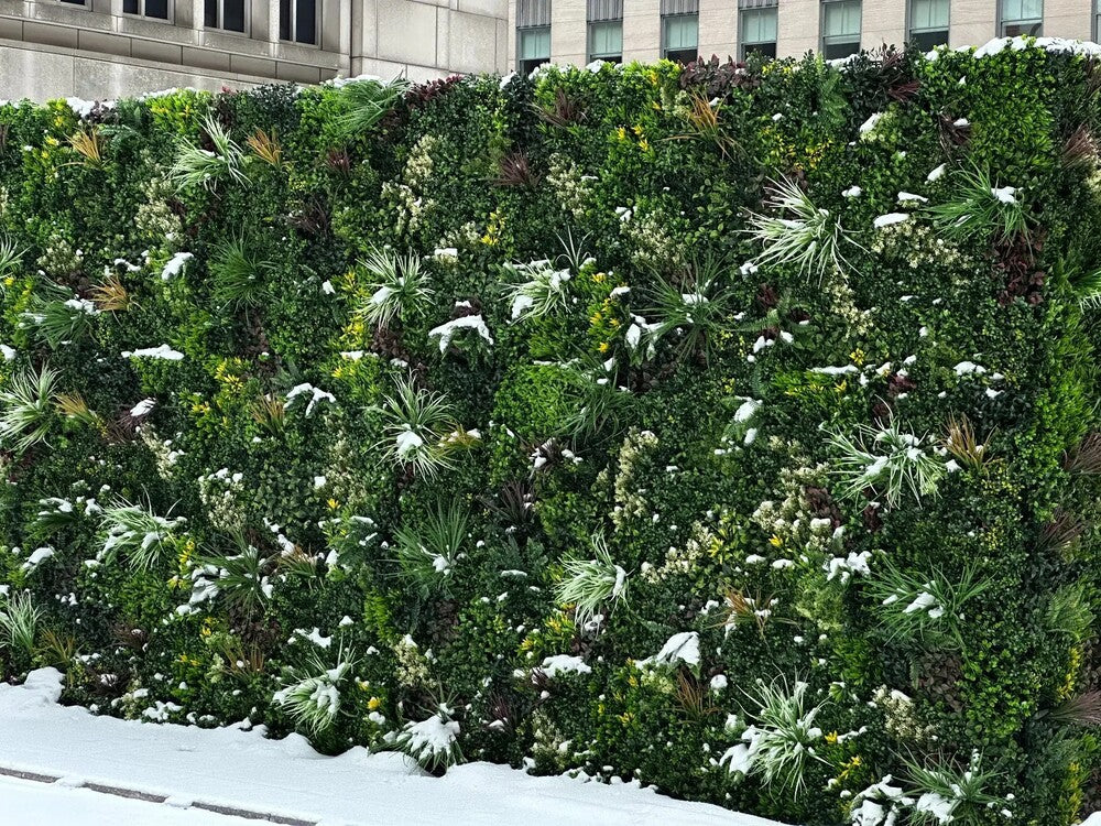 Artificial green wall panels from Designer Plants USA, featuring lush vertical garden with snow-like accents, UV resistant for outdoor use.