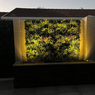 Lush Spring artificial vertical garden panel by Designer Plants USA, UV resistant living wall with vibrant green foliage at night.