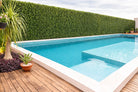 Natural boxwood artificial vertical garden panel by Designer Plants USA, UV-resistant green wall living wall around a pool wall.