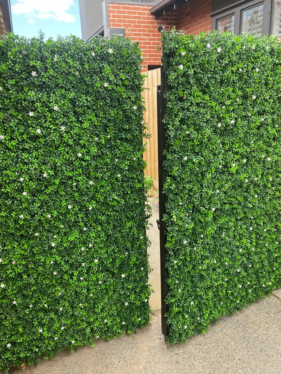 Artificial white flowering boxwood vertical garden panel by Designer Plants USA installed on a gate, UV resistant commercial-grade living wall.
