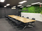 White Oasis artificial green wall panel in a meeting room, showcasing a 40x40 inch UV-resistant living wall by Designer Plants USA.