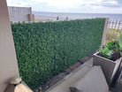 Small sample of Designer Plants USA artificial boxwood hedge panel in natural green, installed on a fence.