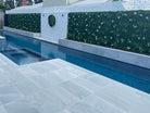 Small sample of Designer Plants USA Snowy White vertical garden panel with artificial flowers, green wall, and poolside setting.