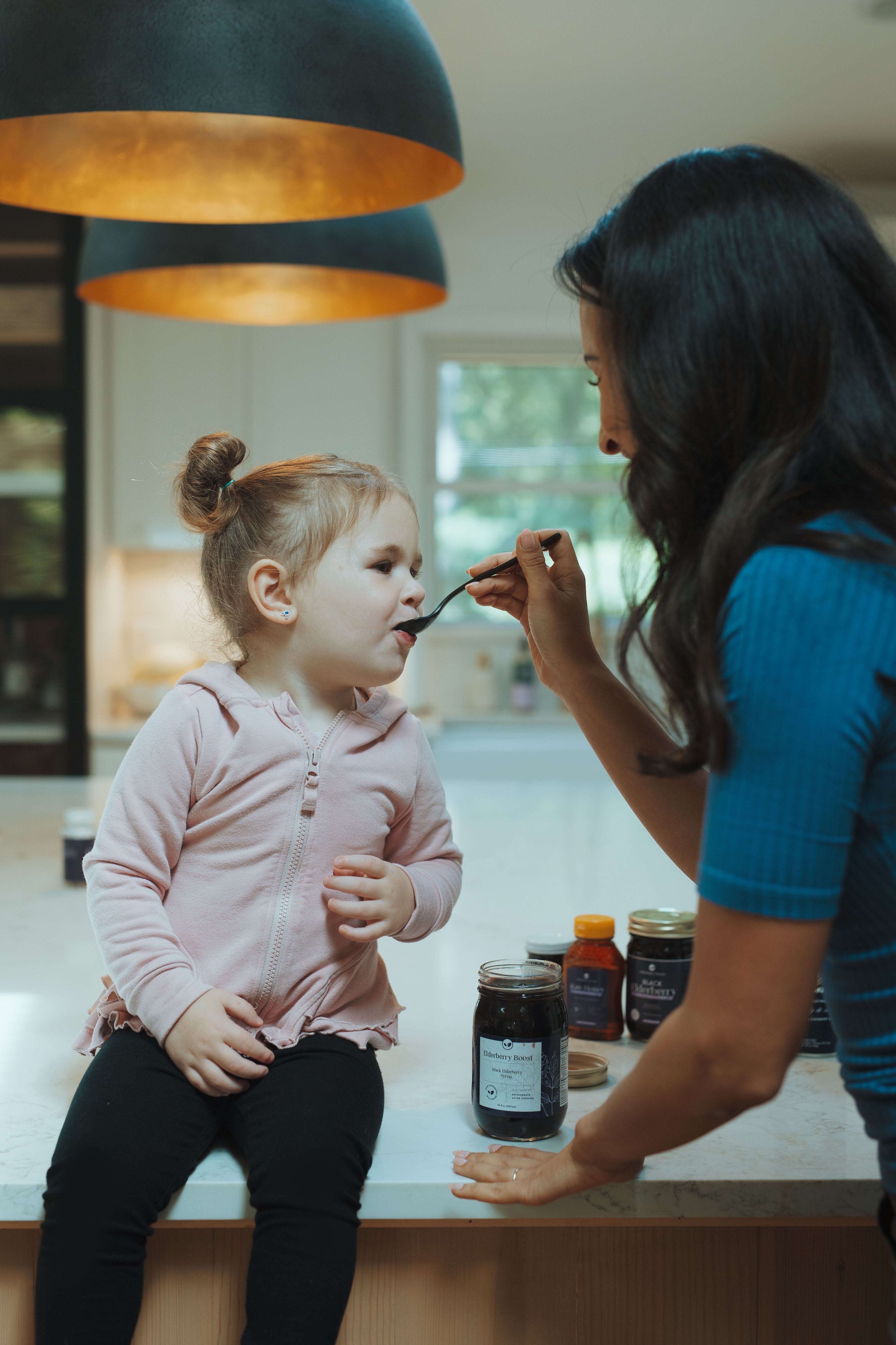 All-natural elderberry syrup in a 16 oz bottle by Elderberry Boost, LLC, with fresh elderberries and a natural syrup consistency.