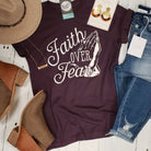 Dark purple graphic T-shirt with "Faith Over Fear" text from The Graphic Tee, showcasing a casual, inspirational design.