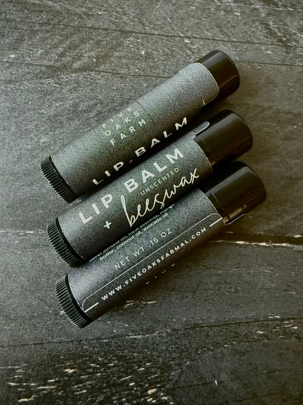 Unlabeled beeswax lip balm from Five Oaks Farm with natural, unscented formula in a small container.