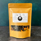 A bowl of Five Oaks Farm from-the-farm Chai Tea Mix with spices and tea leaves on a rustic wooden surface.
