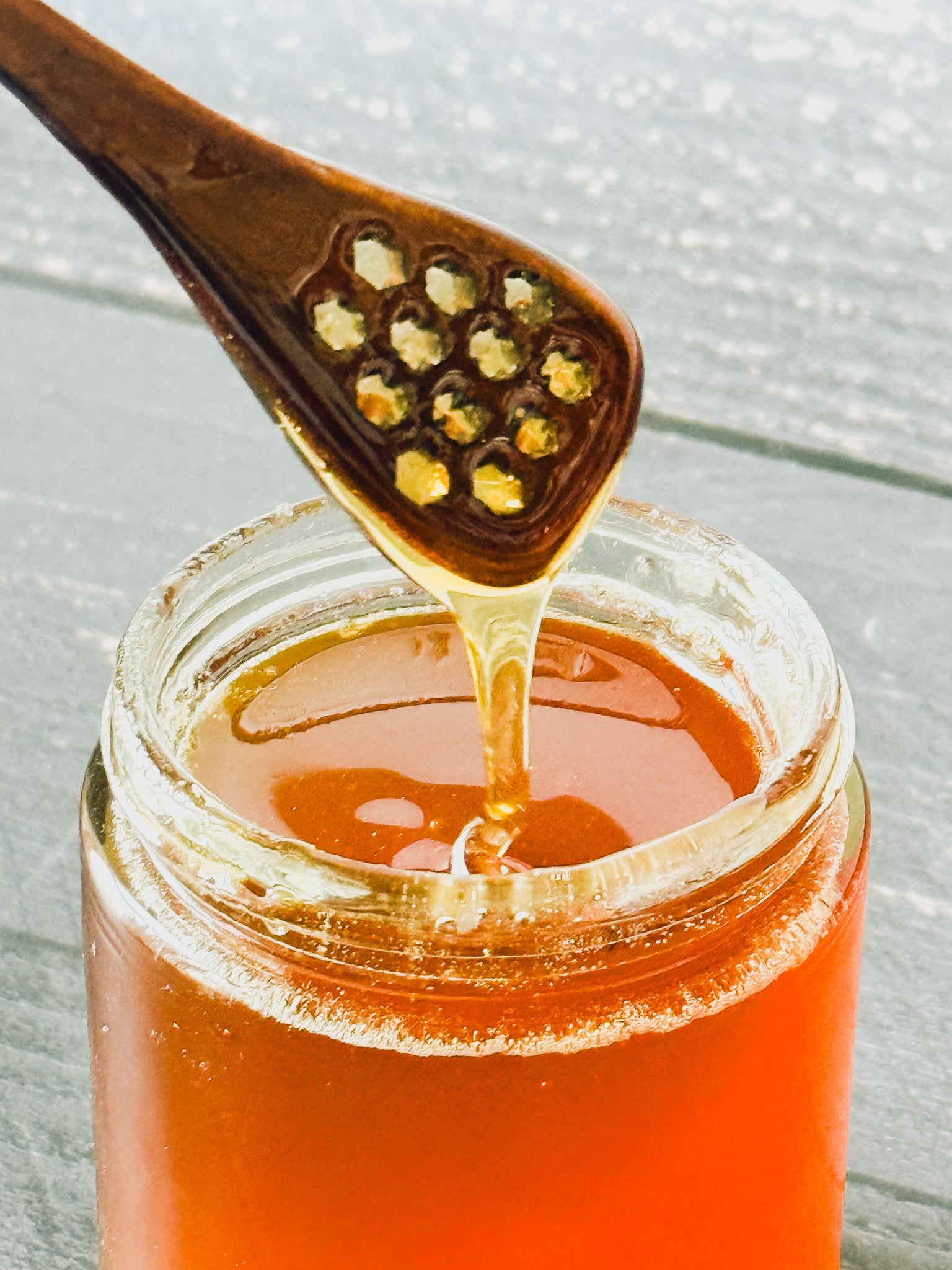 Honey spoon from Five Oaks Farm with wooden handle and honey drizzled on the spoon for serving and tasting.