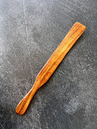 Rustic wooden spurtle from Five Oaks Farm, designed for stirring and serving, displayed on a natural kitchen setting.