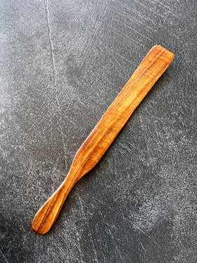 Rustic wooden spurtle from Five Oaks Farm, designed for stirring and serving, displayed on a natural kitchen setting.
