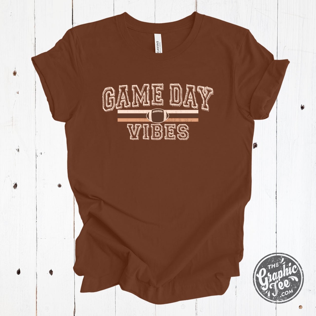 Graphic SS football T-shirt from The Graphic Tee with "Game Day Vibes" design, featuring football graphics and vibrant colors.