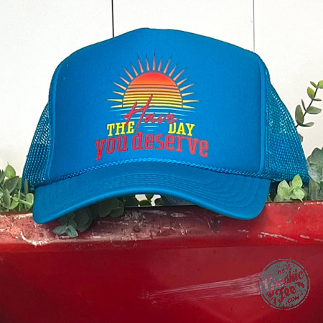 Foam trucker cap from The Graphic Tee with "Have the Day You Deserve" slogan, featuring a mesh back and adjustable strap.