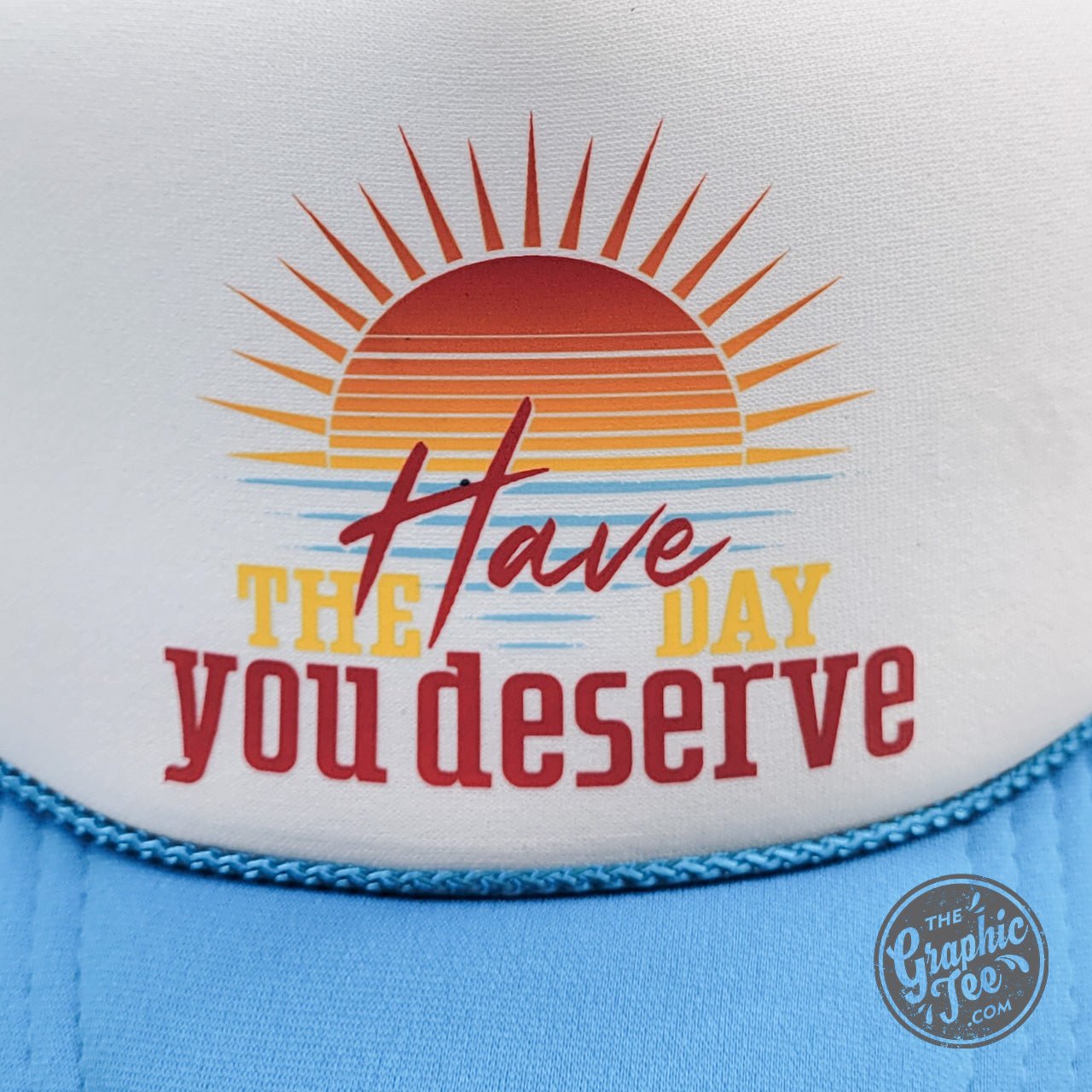 Neon blue and white foam trucker cap with "Have the Day You Deserve" text by The Graphic Tee, adjustable snapback style
