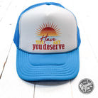 Neon blue and white foam trucker cap with "Have the Day You Deserve" slogan by The Graphic Tee, adjustable mesh back, casual style.