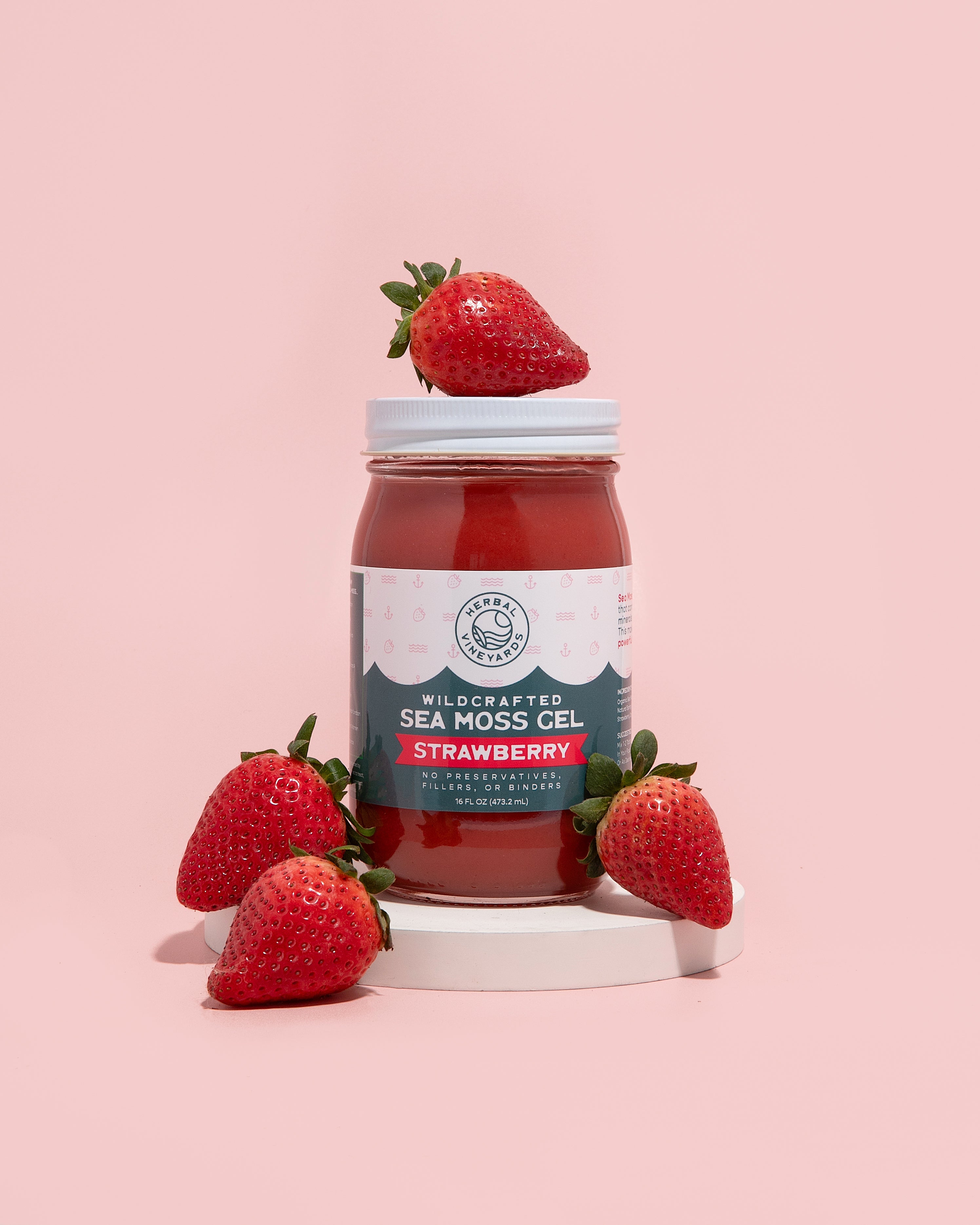 Herbal Vineyards strawberry sea moss gel in a clear jar with a spoon, showcasing the vibrant pink color and fresh texture.
