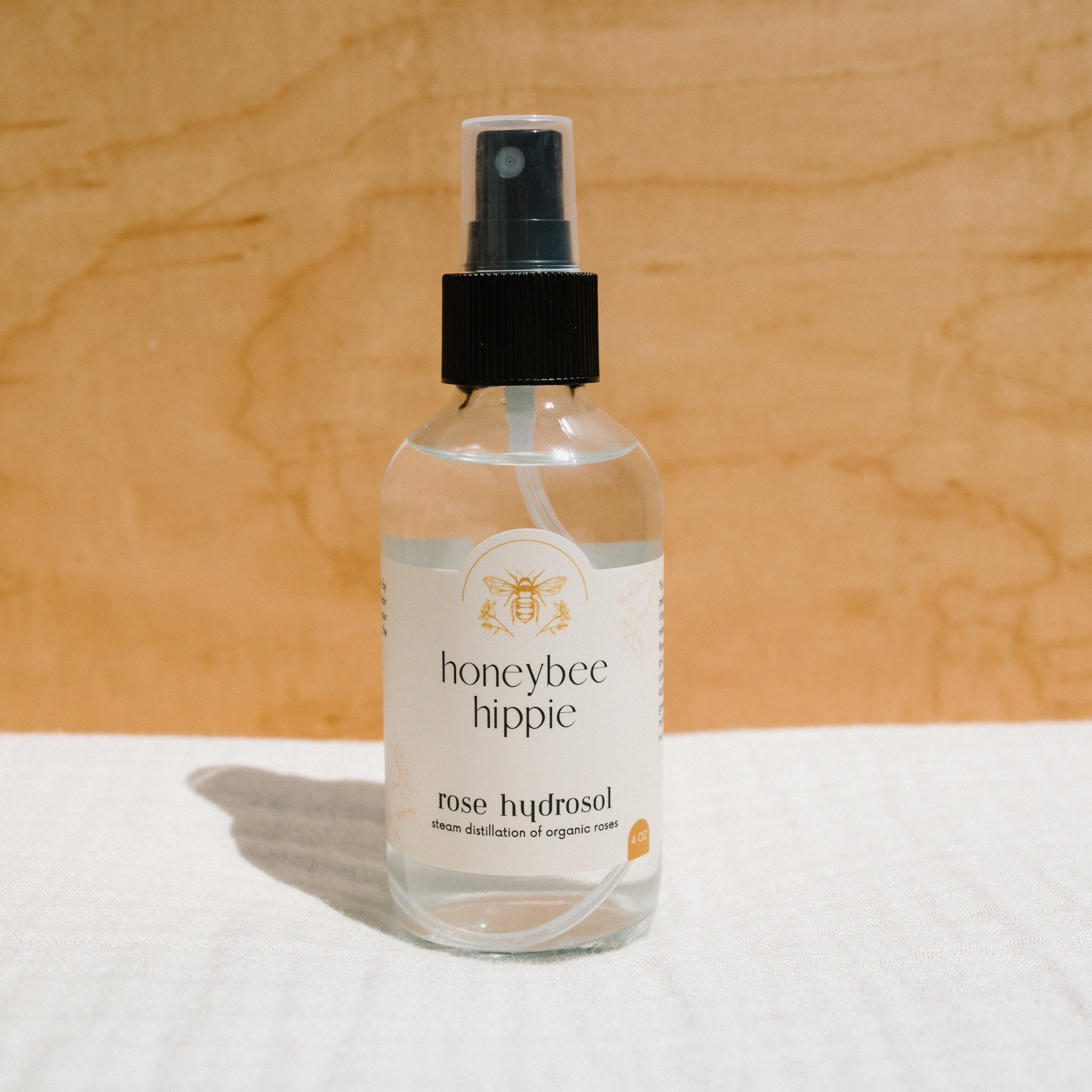 Face of Honeybee Hippie rose hydrosol bottle with spray nozzle, showcasing natural floral skincare product.