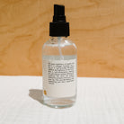 Face with a spray bottle of Honeybee Hippie Rose Hydrosol, natural facial mist with rose water for skincare.