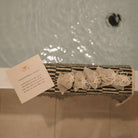 Herbal sitz bath by Honeybee Hippie for postpartum recovery, showing a herbal bath soak in a rustic wooden tub.