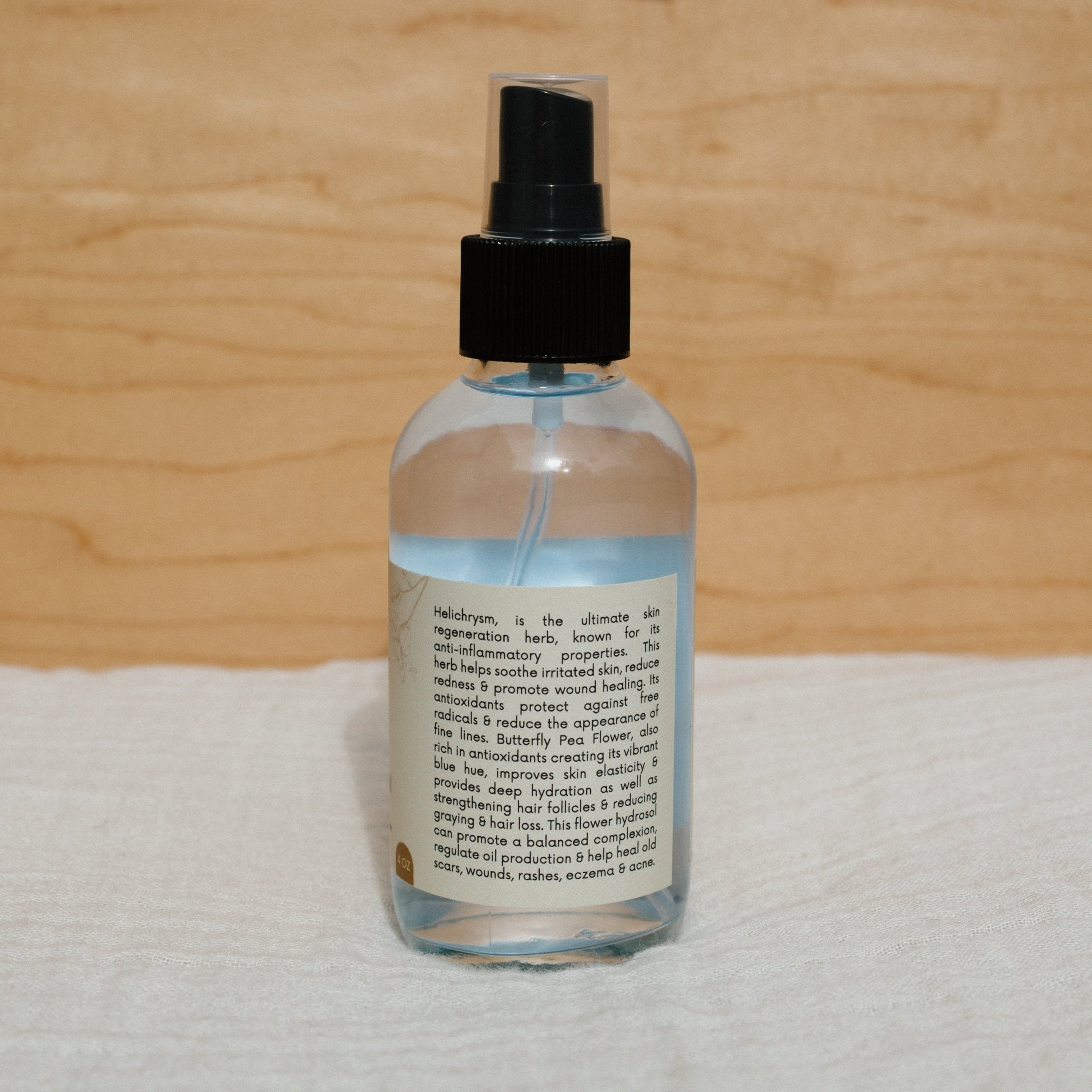 Butterfly hydrosol by Honeybee Hippie, a natural floral water with a clear bottle and label, showcasing the product in a glass container.