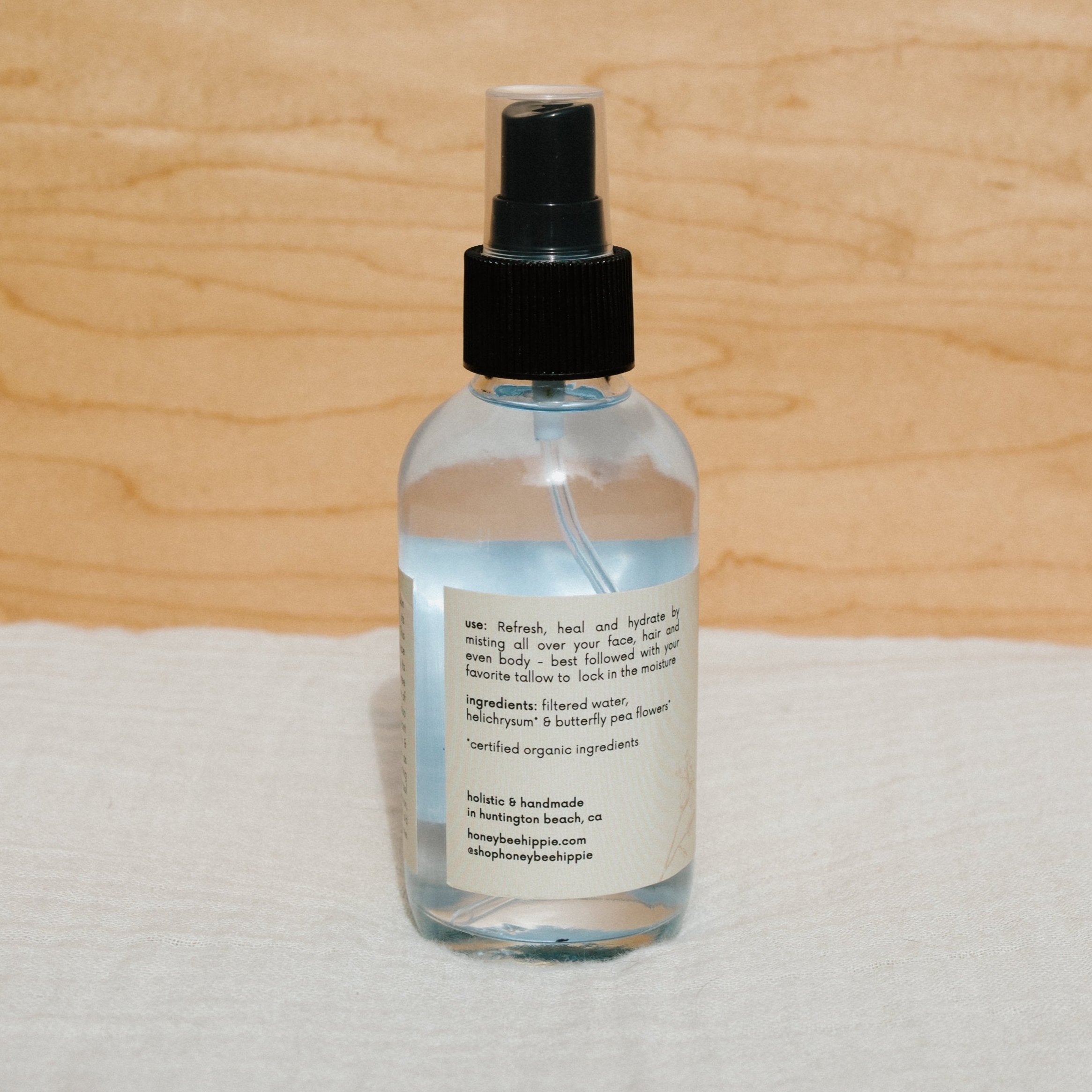 Bottle of Honeybee Hippie Butterfly Hydrosol with floral label, showcasing a natural floral hydrosol product in a clear glass bottle.