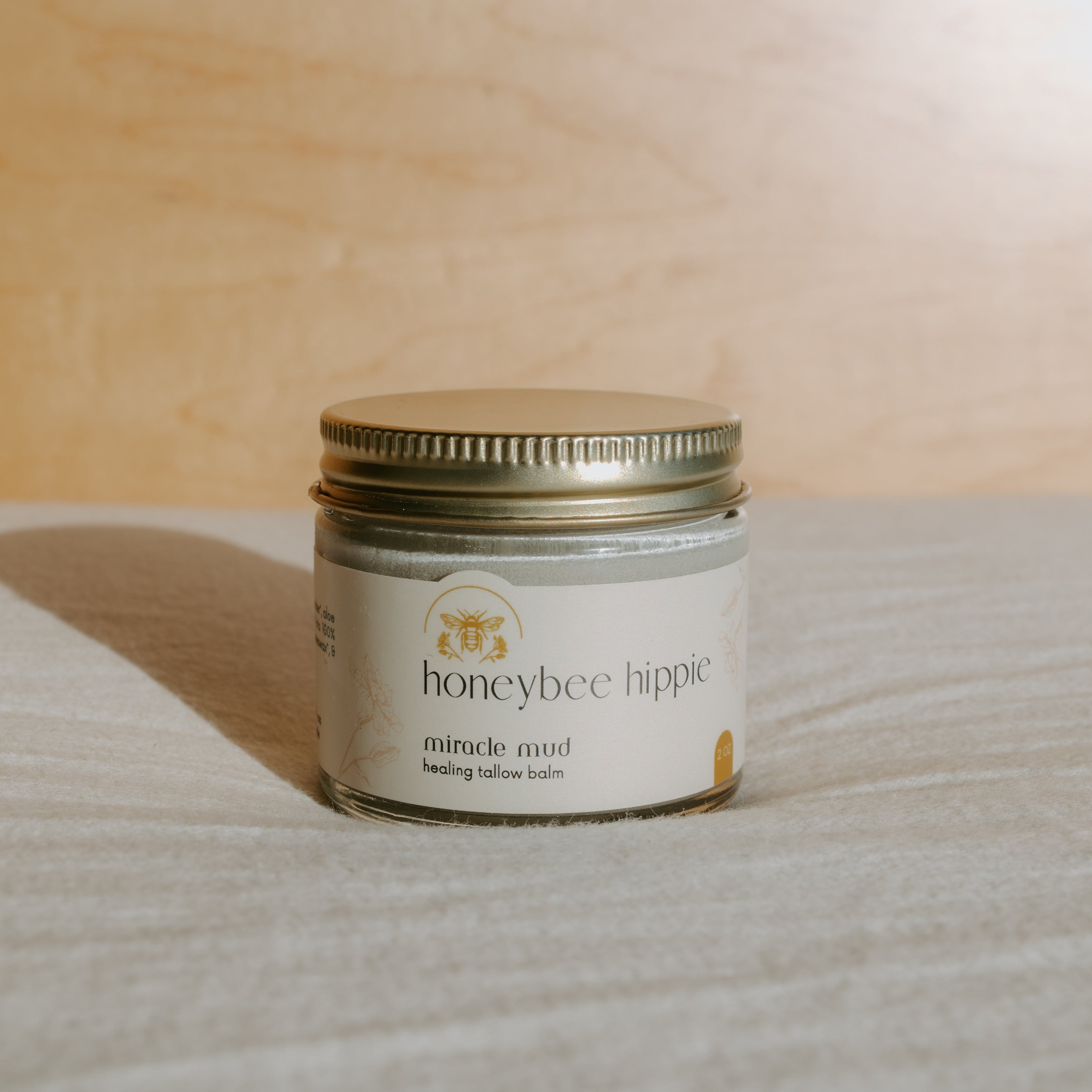 Honeybee Hippie Miracle Mud jar with a natural clay mask, showcasing its earthy texture and brand label on the container.