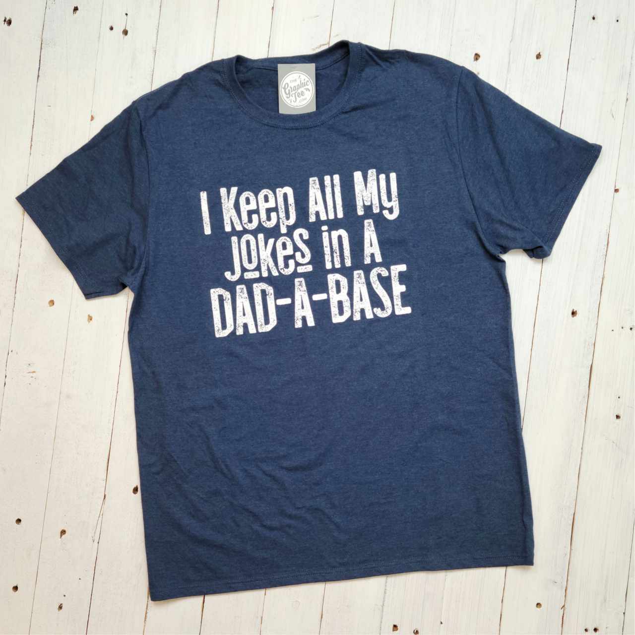 Adult graphic tee by The Graphic Tee featuring the humorous "I Keep All My Jokes In A Dad-A-Base" design on a short-sleeve shirt.