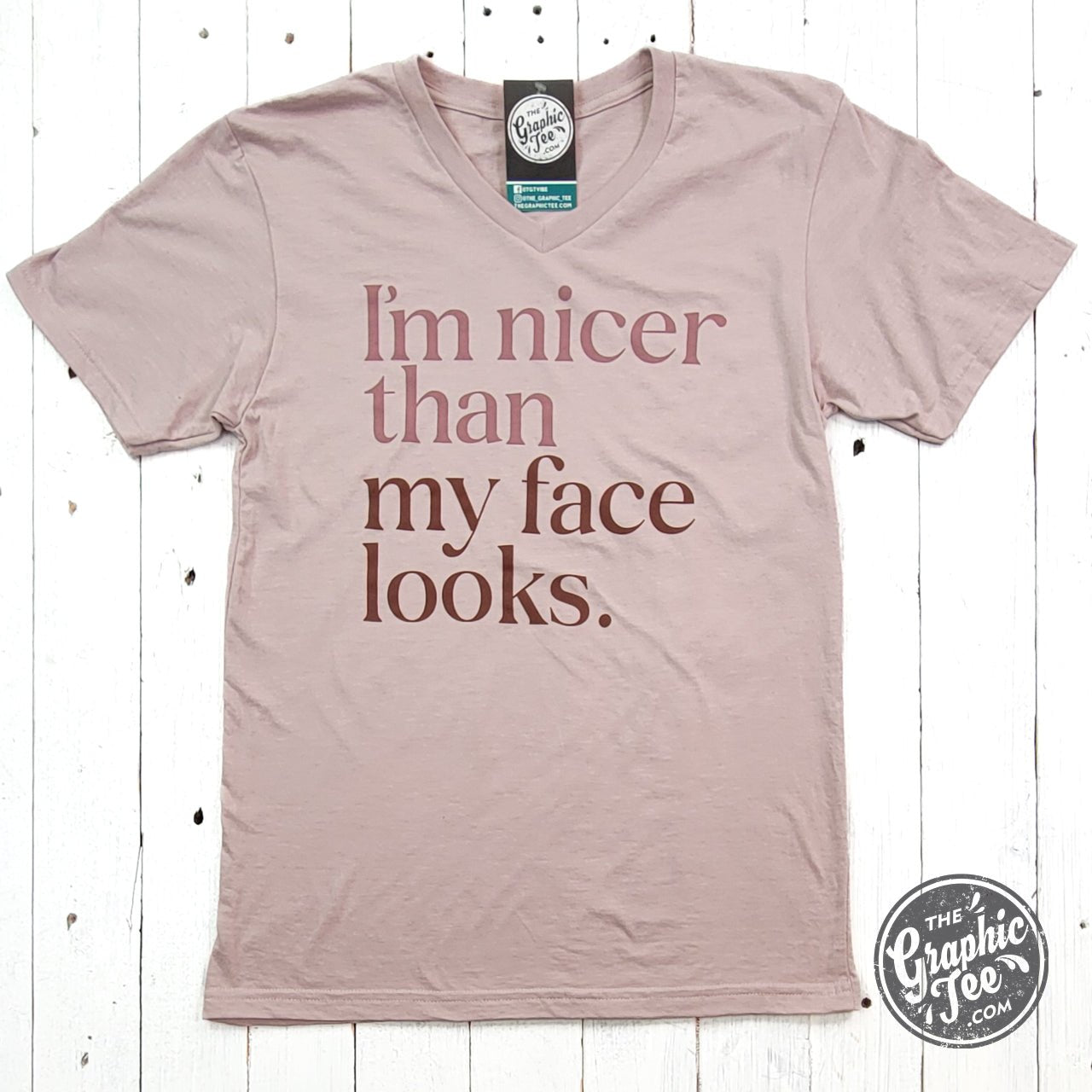 Black V-neck graphic t-shirt by The Graphic Tee reading "I'm Nicer Than My Face Looks" in bold white letters.