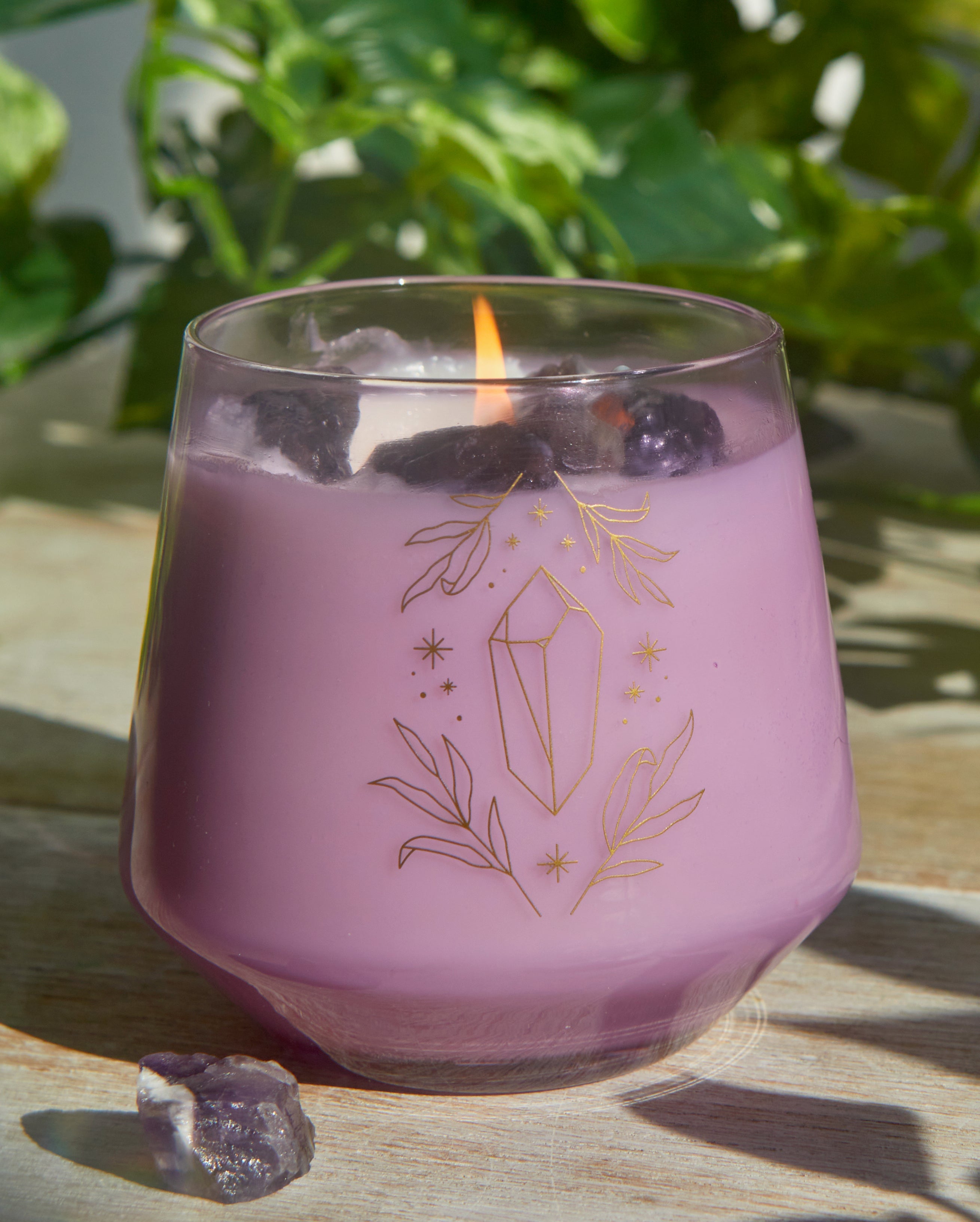 Amethyst crystal healing scented glass candle on a wooden surface, showcasing the purple gemstone and decorative candle holder.
