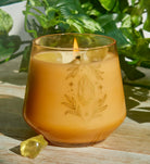Citrine crystal healing scented glass candle on a wooden table, surrounded by decorative items in a cozy home interior.